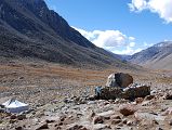 59 Eastern Valley After Descent From Dolma La With A Buddha Footprint Imbedded On Top Of Large Boulder On Mount Kailash Outer Kora The trail took an hour to reach the Eastern Valley (5235m,10:15) from the Dolma La. To the right of the trail beside a stone wall is Buddha footprint imbedded on top of the boulder. The pilgrims who run the seasonal nomad refreshment tent were packing up for the seasons and heading home.